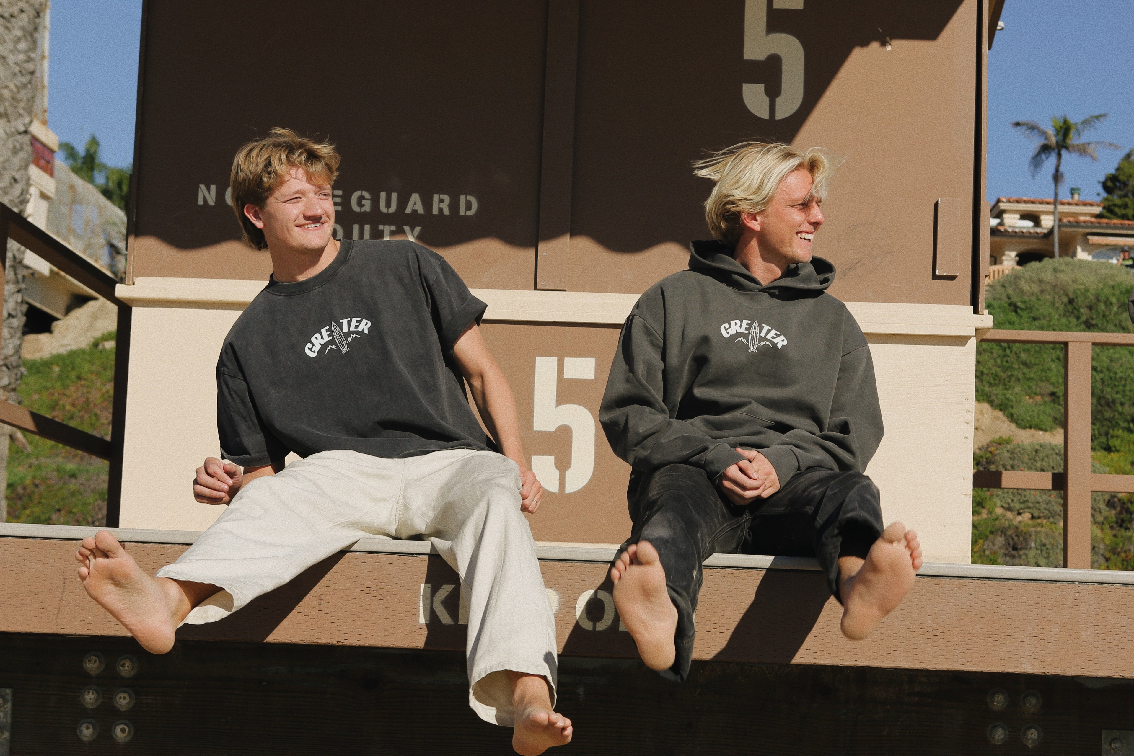 Two people sitting on a wooden bench with a scenic background